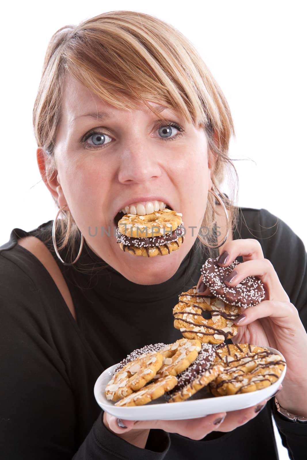 Attractive young woman with her mouth and hands full of cookies