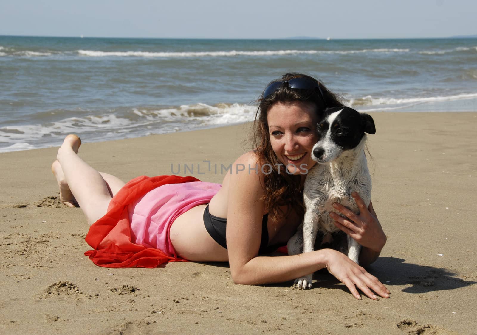 happy young woman on the beach with her little dog