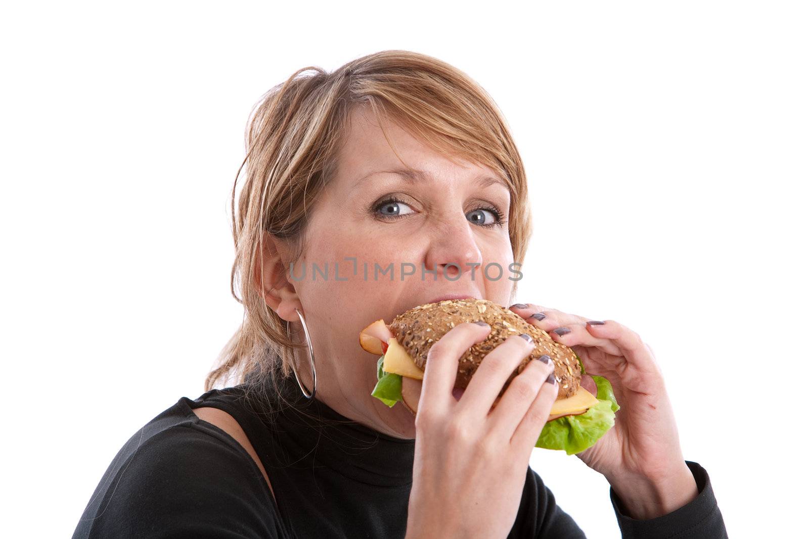Pretty blond woman taking a big bite out of a healthy sandwich