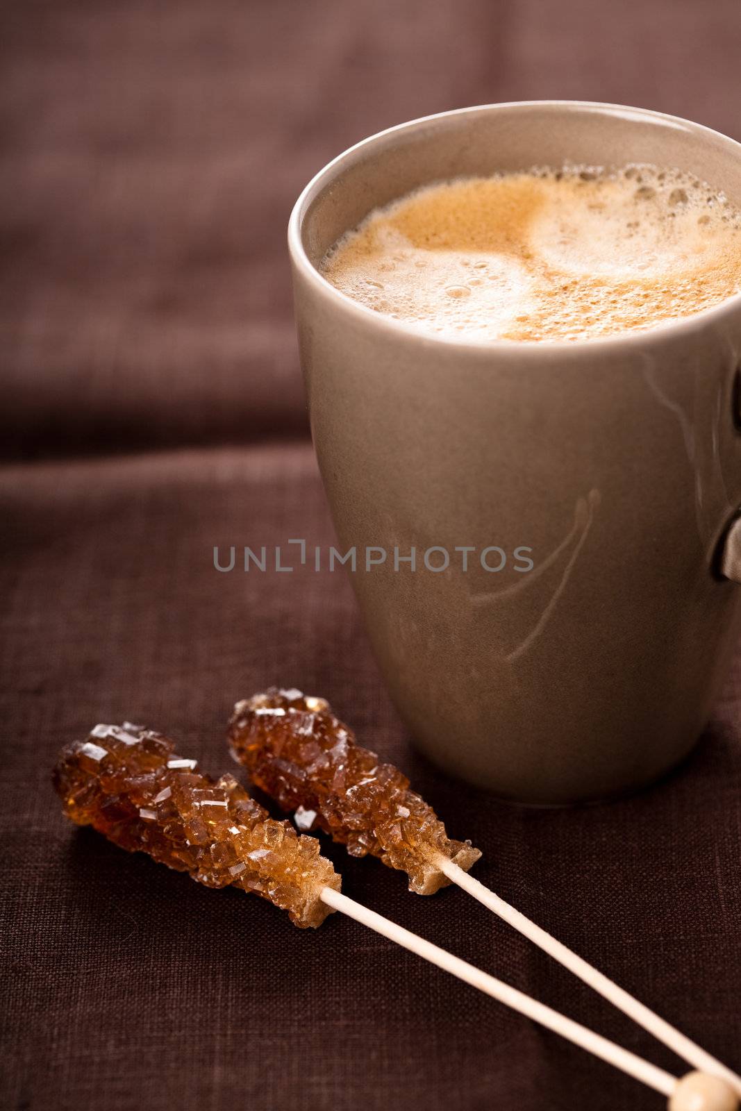 Delicious cup of coffee with sugar canes next to it