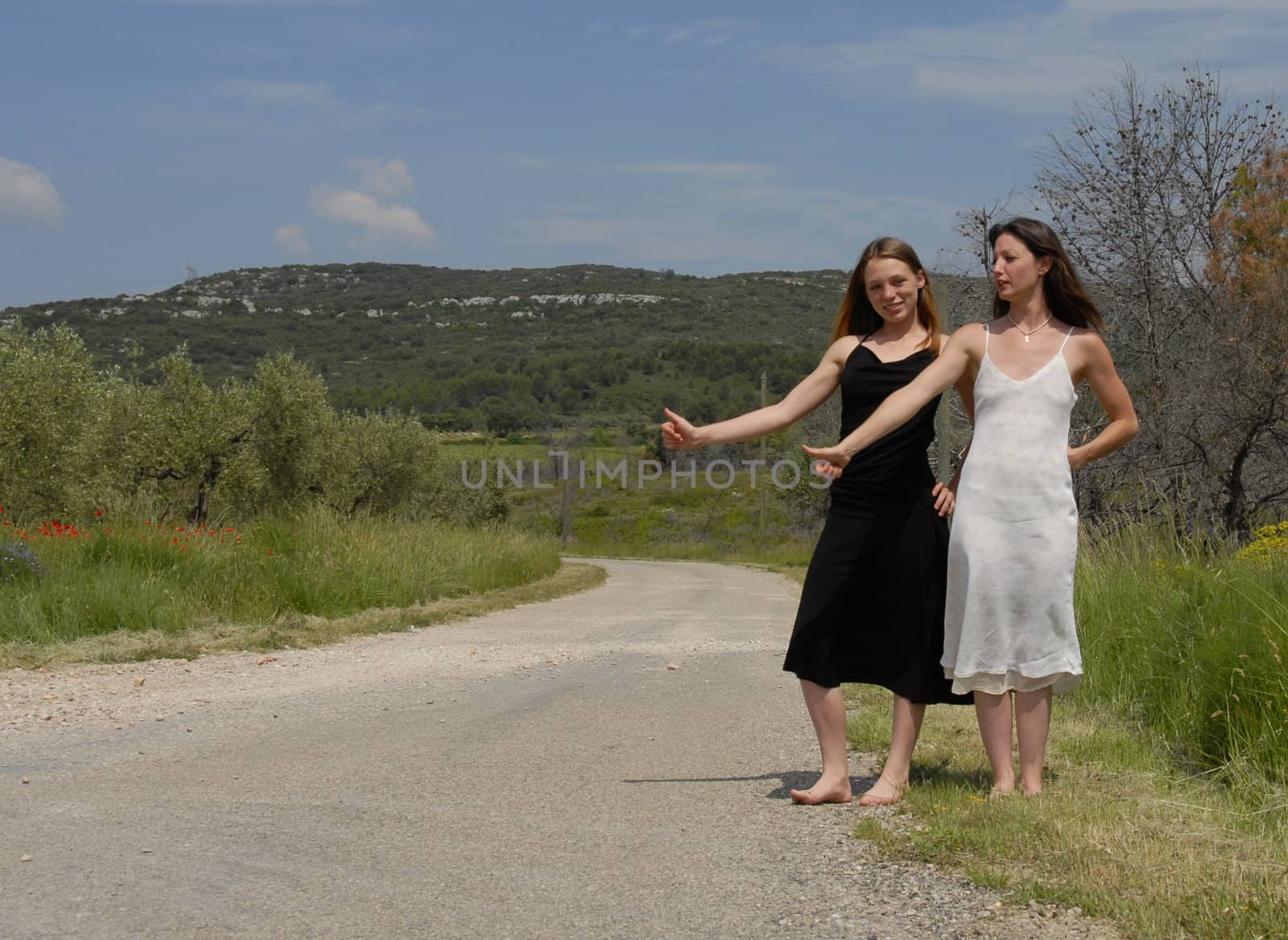 two beautiful young woman hitchhiking on a rural road