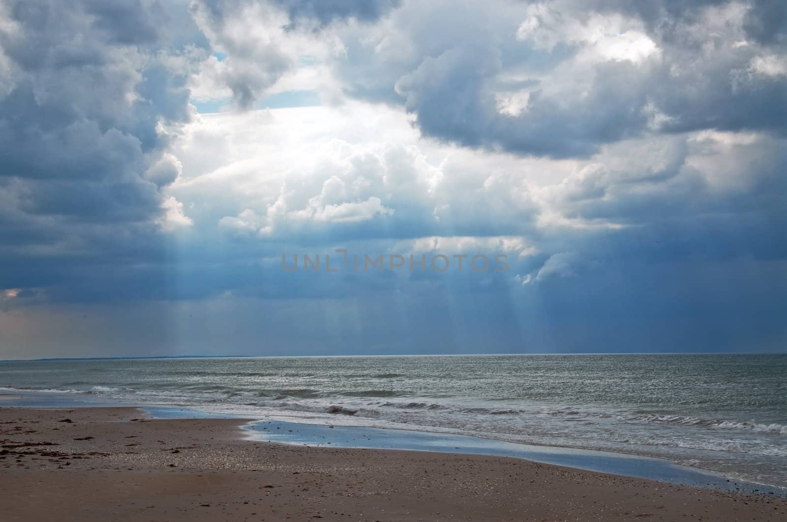 Dark clouds and sun rays at the beach