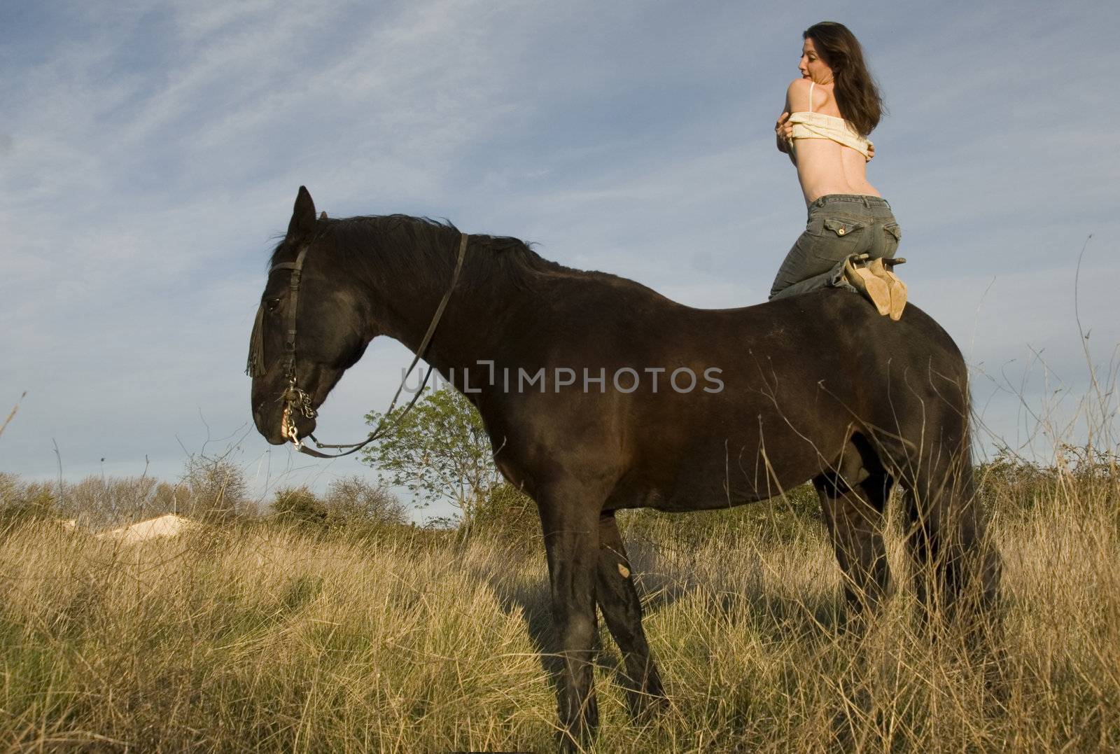 happy girl and her black stallion in a field