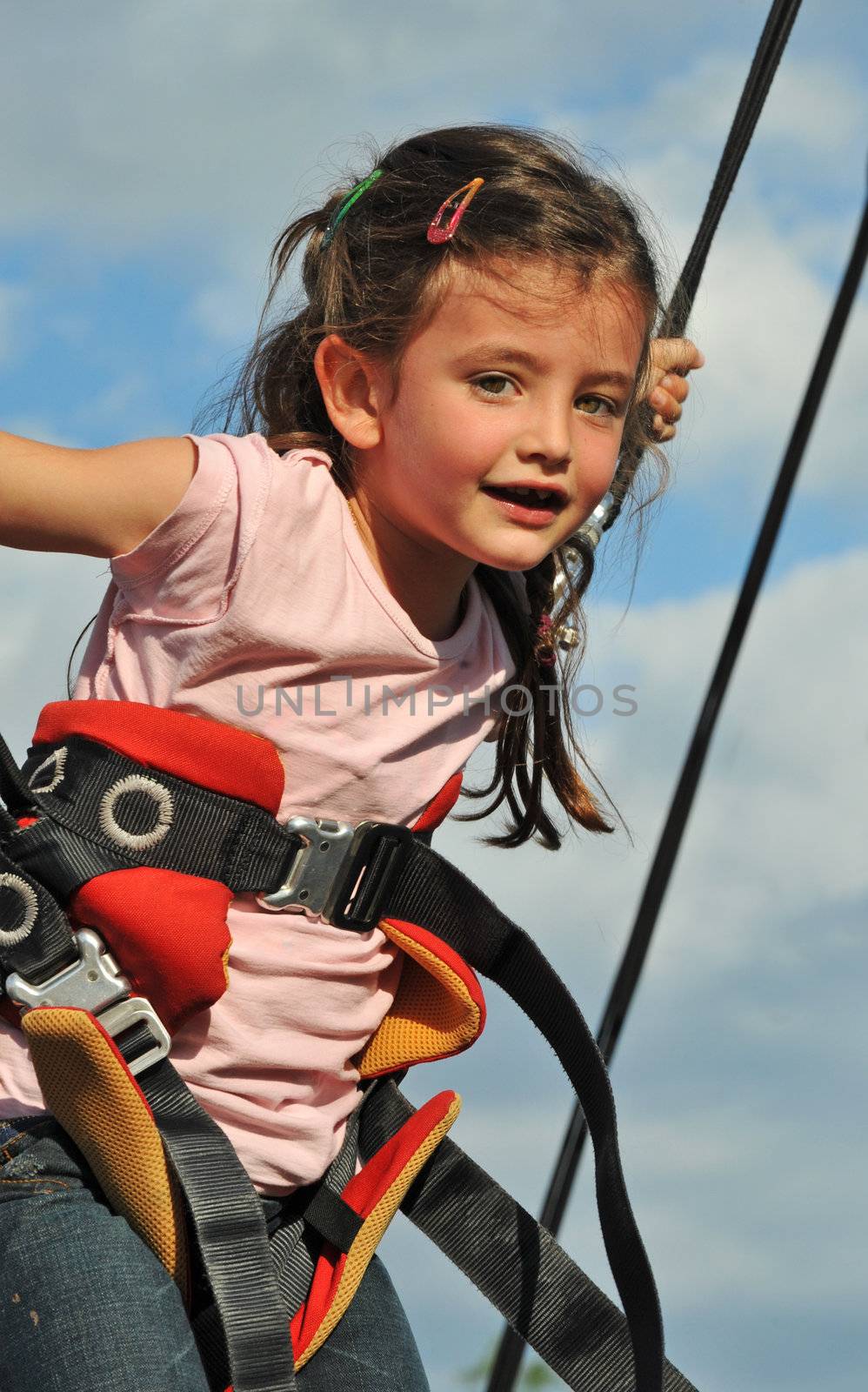 Little girl jumping on the trampoline (bungee jumping).