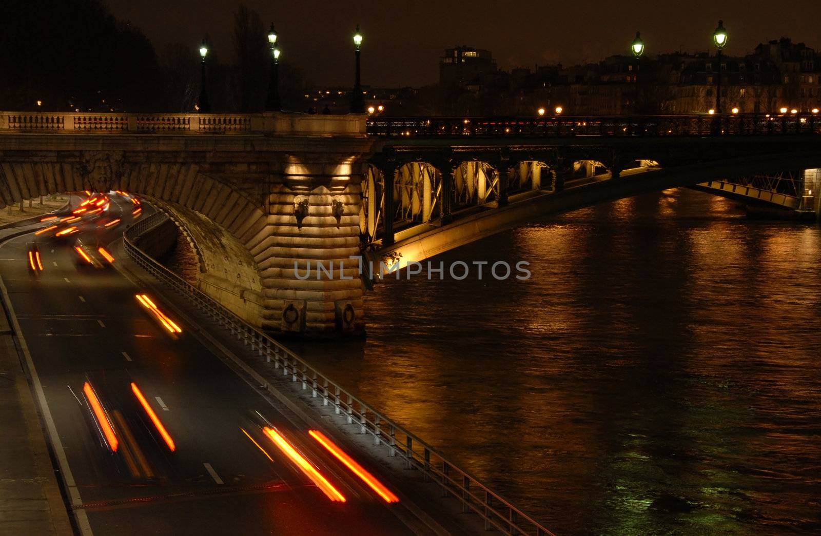 Traffic on a highway at night under a bridge in Paris (France).