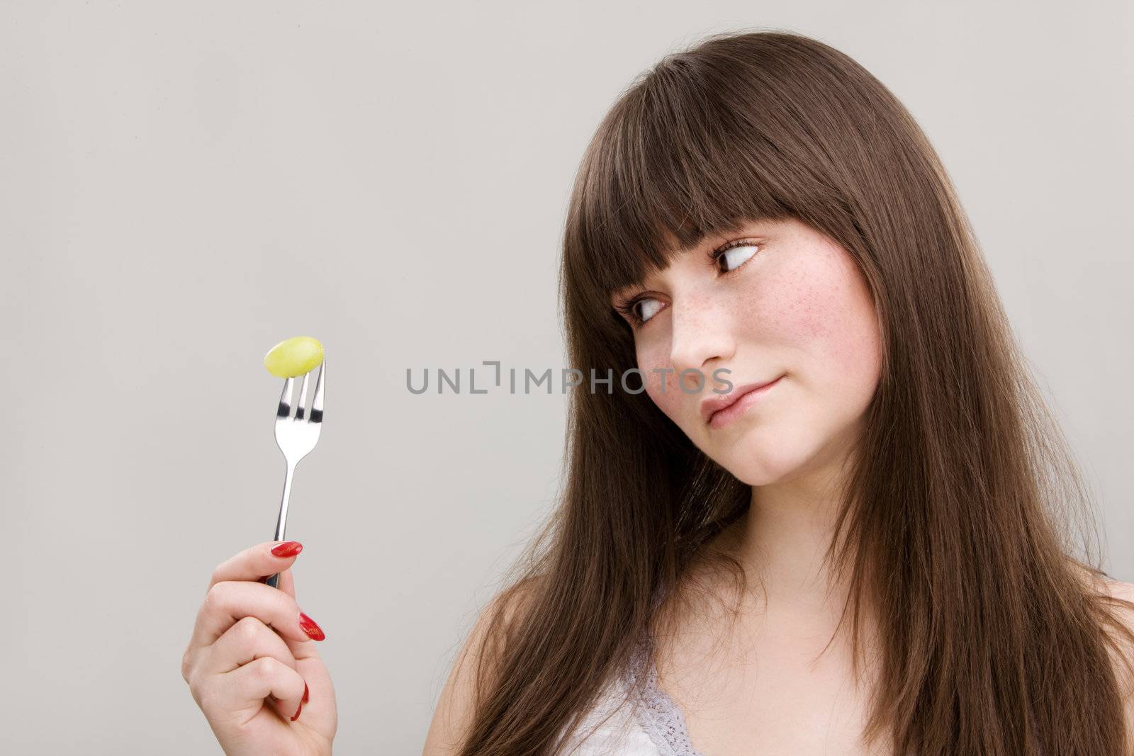 Portrait of young girl holding fork with a grape