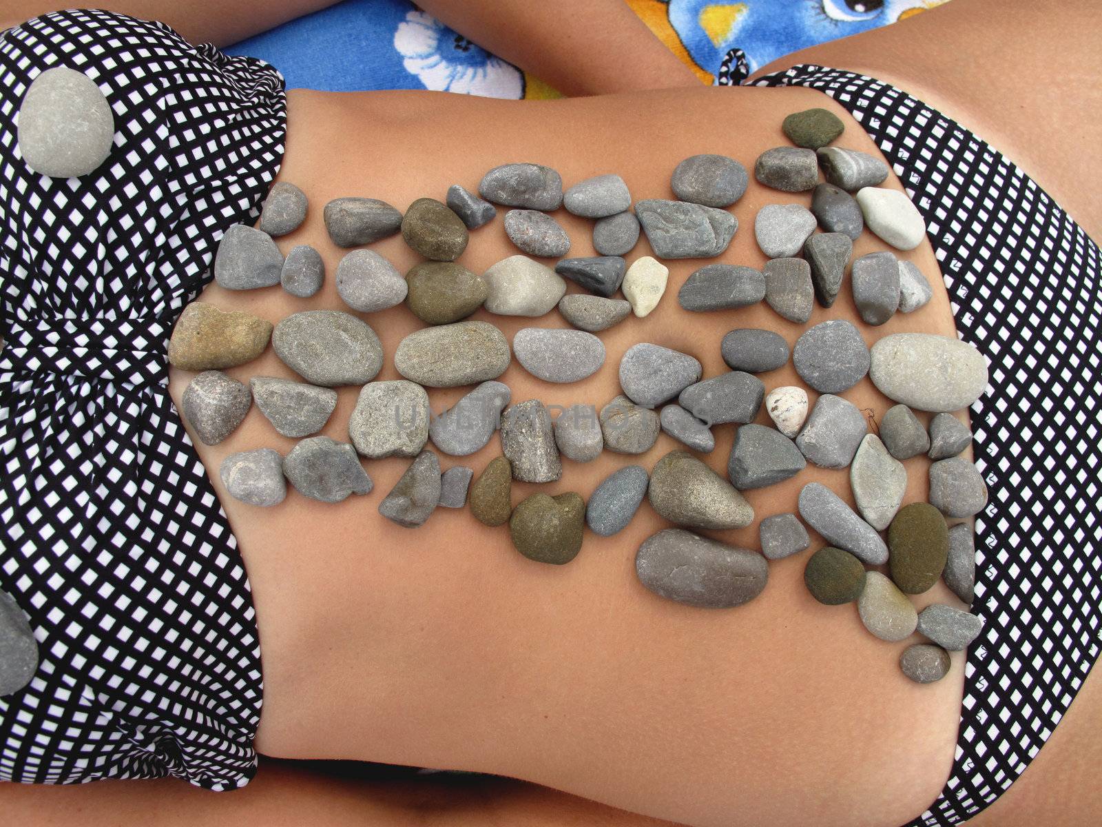 Small stones on a female stomach, taken on the beach resot                             