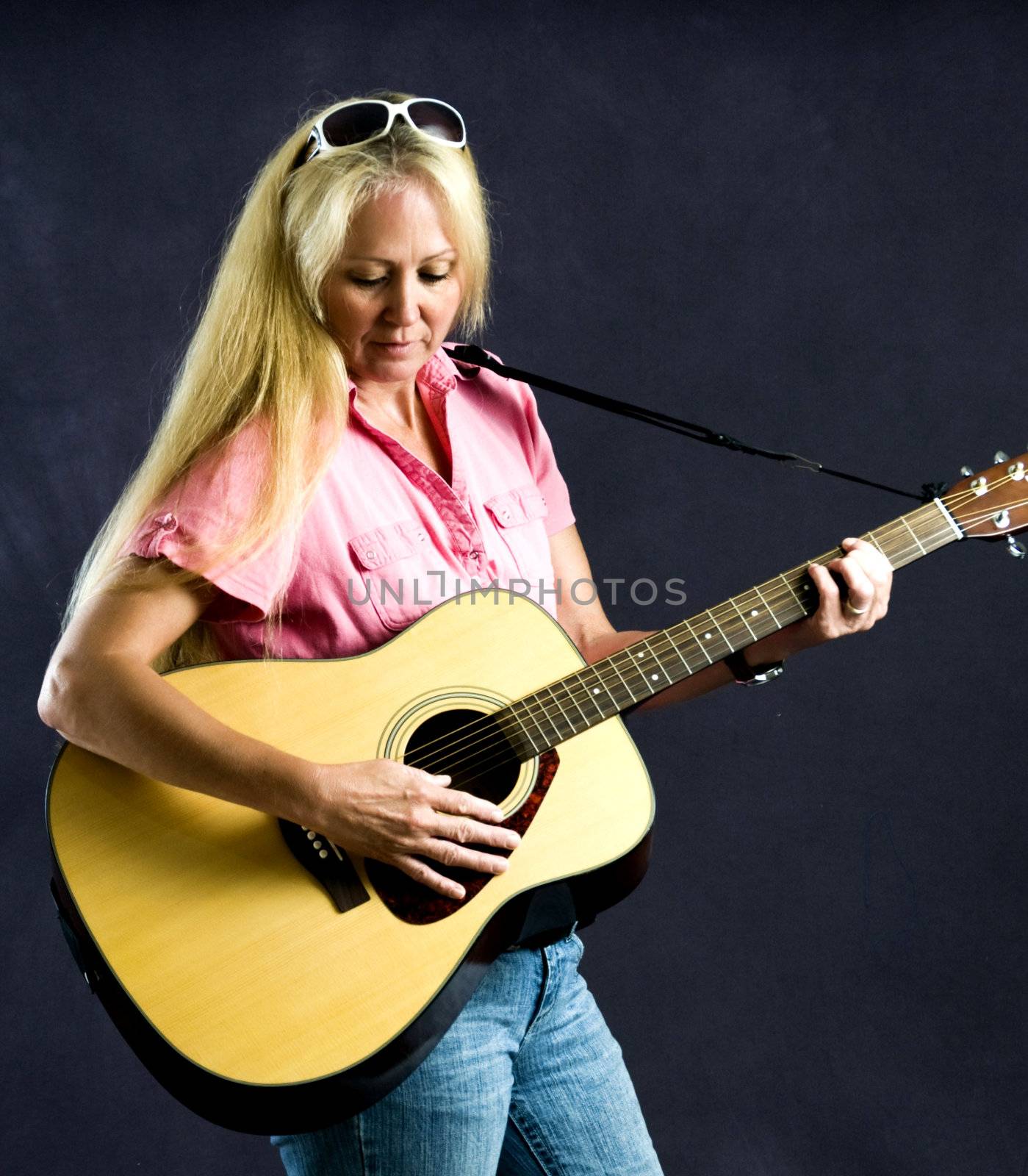 Pretty woman playing folk music on an acustical guitar.