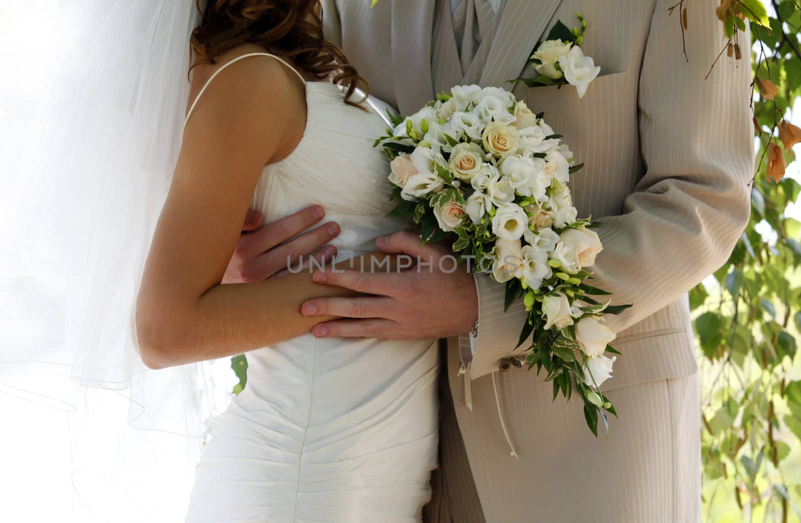 Bouquet of flowers on a background of a dress of the bride and a suit the groom.