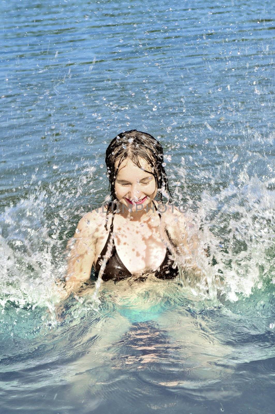 Young girl playing and splashing in a lake