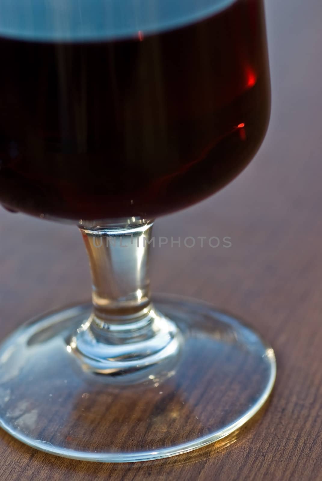 A glass of red wine on a wooden table.