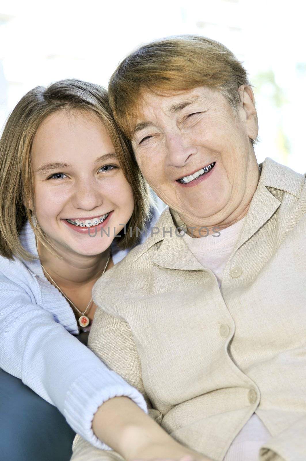 Teen granddaughter hugging grandmother laughing and smiling