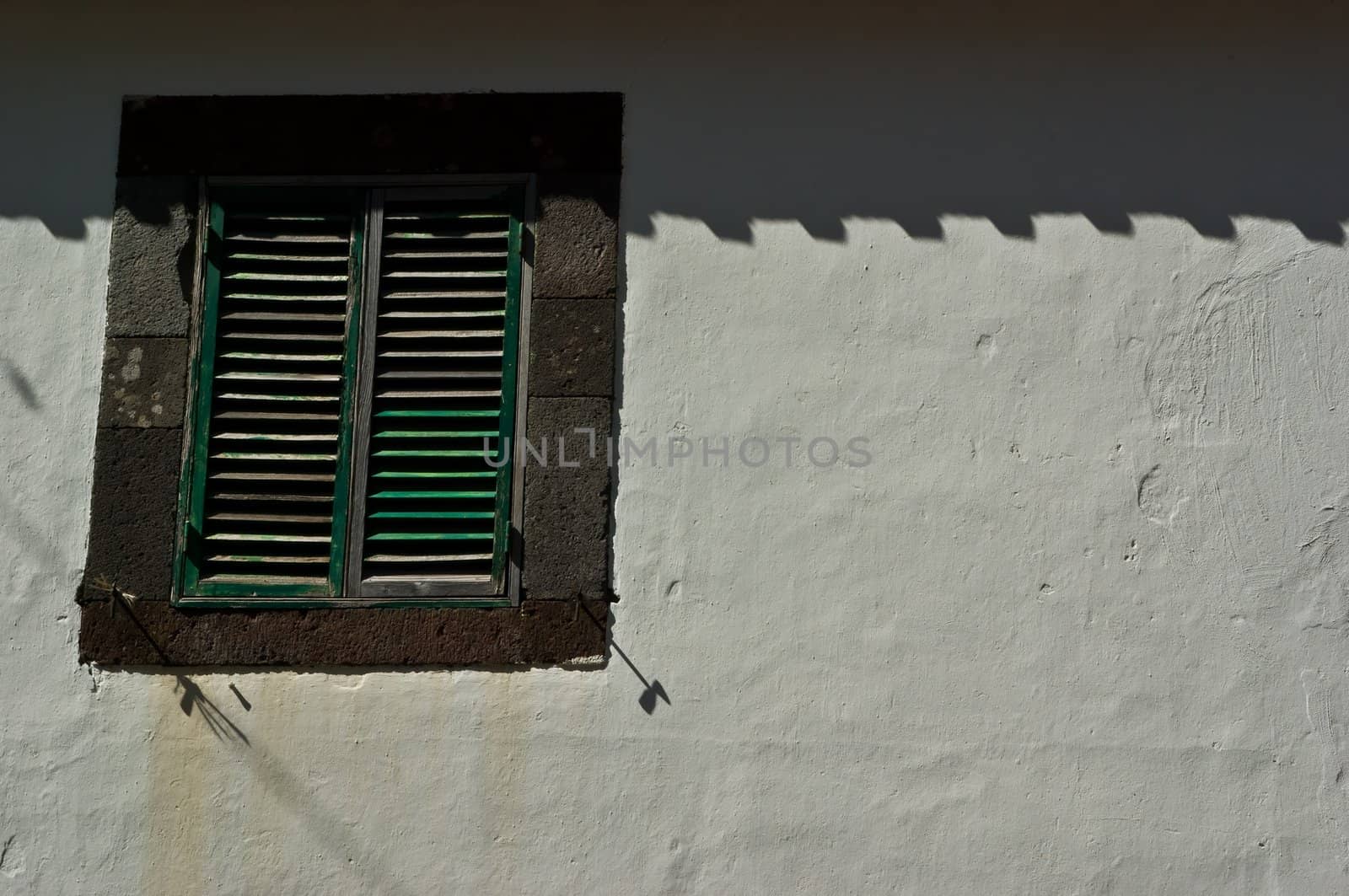 Window with blinds in a white wall, taken on Madeira, Portugal.