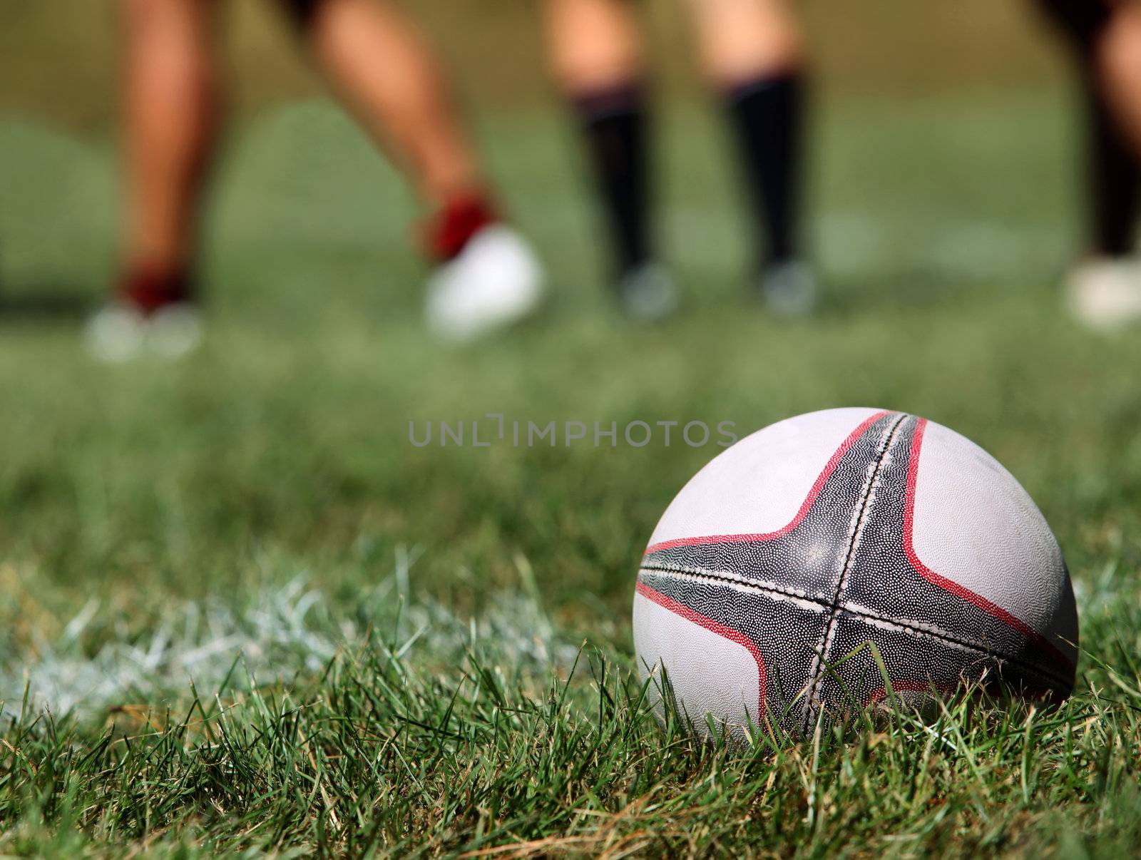 Rugby ball on a grass on a background of legs of players