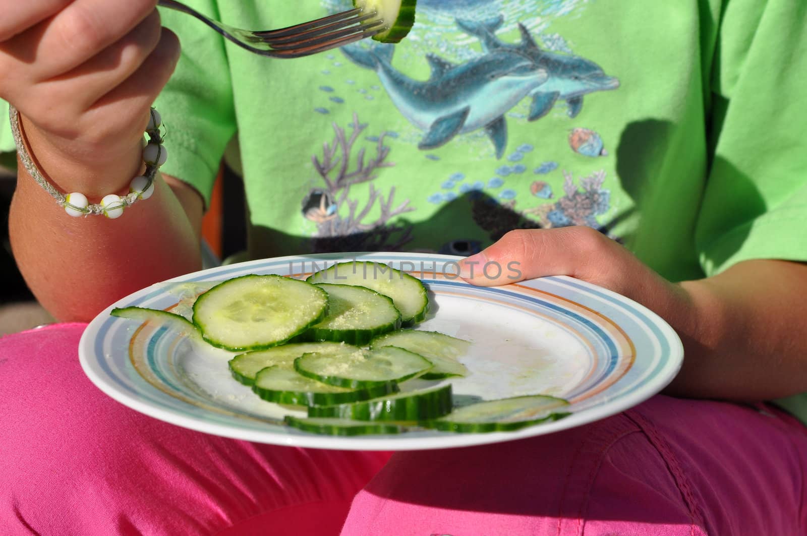 A girl having some cucumber slices.
