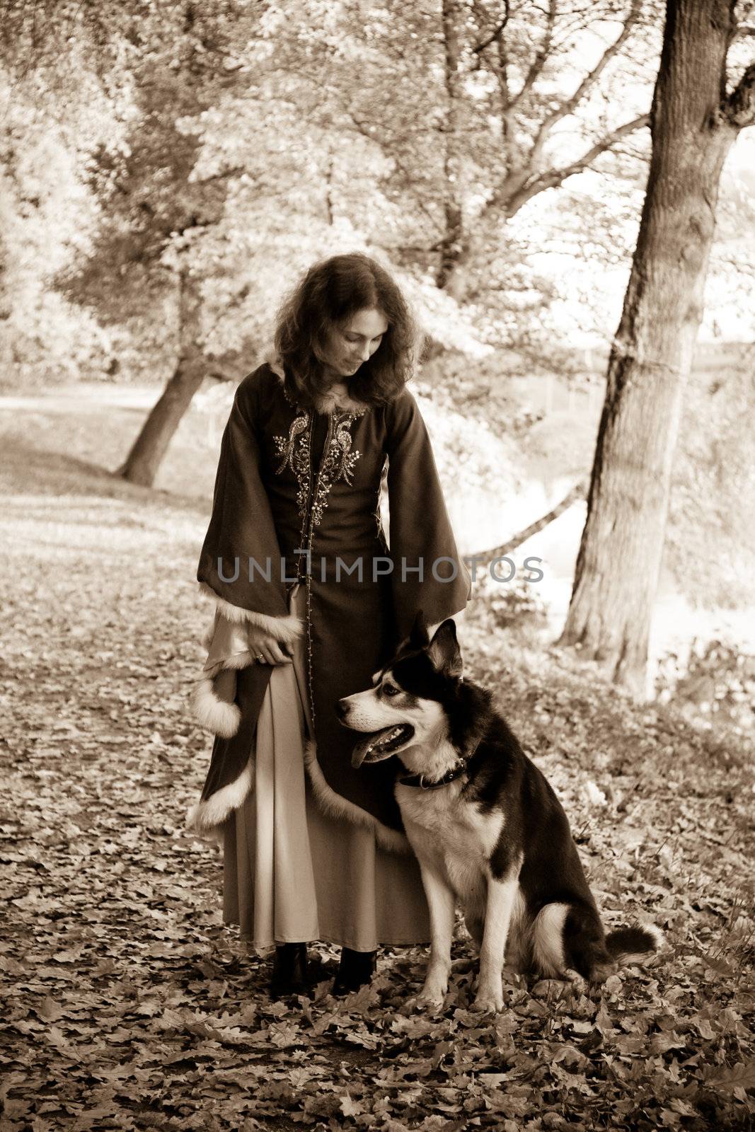 Lady in medieval dress and dog in the forest
