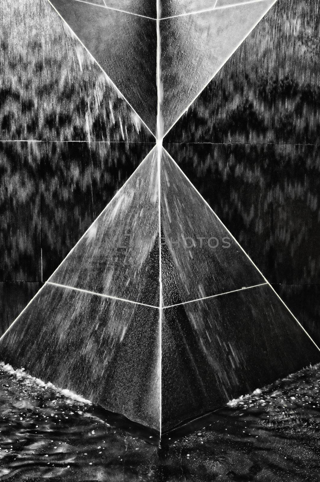 A select portion of a black granite fountain structure with triangular and pyramid geometric shapes.