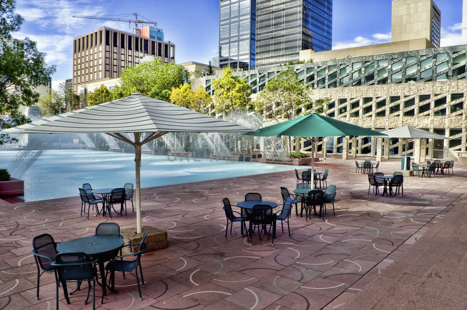 Late August image of the tables, chairs and umbrellas near the fountain pool in front of city hall in Edmonton, Alberta, Canada.