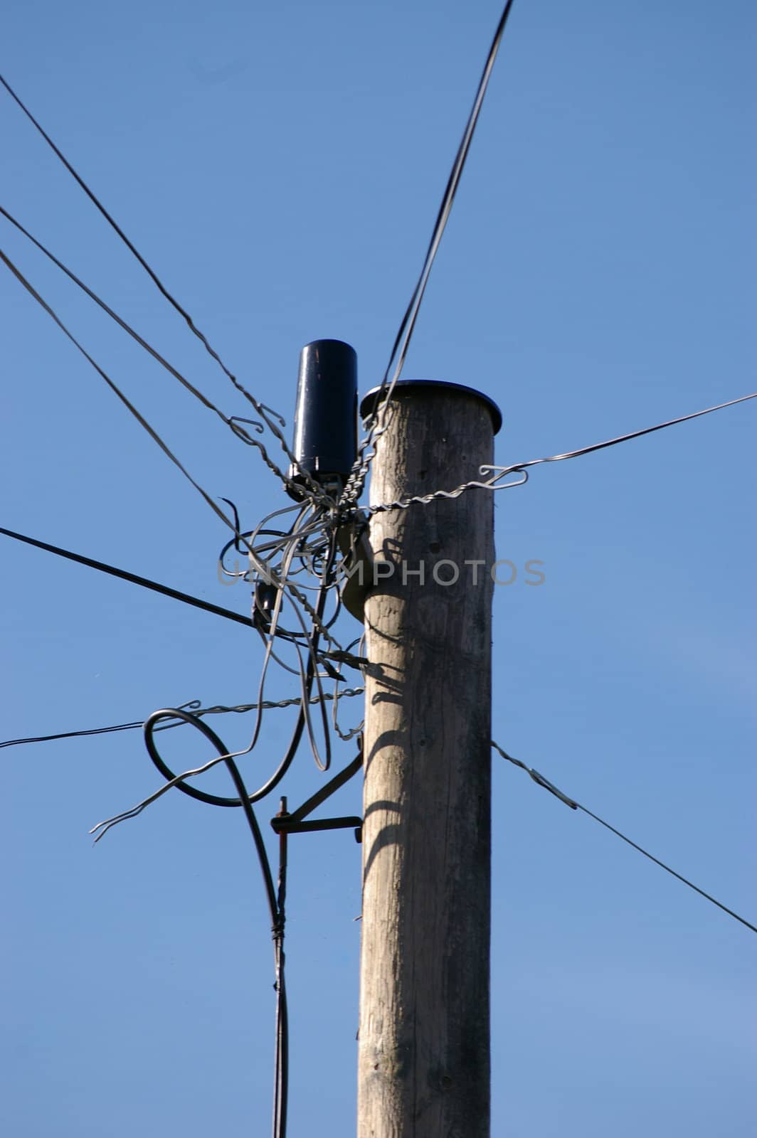 The top of a phone pole with a mess of wires going in different directions.