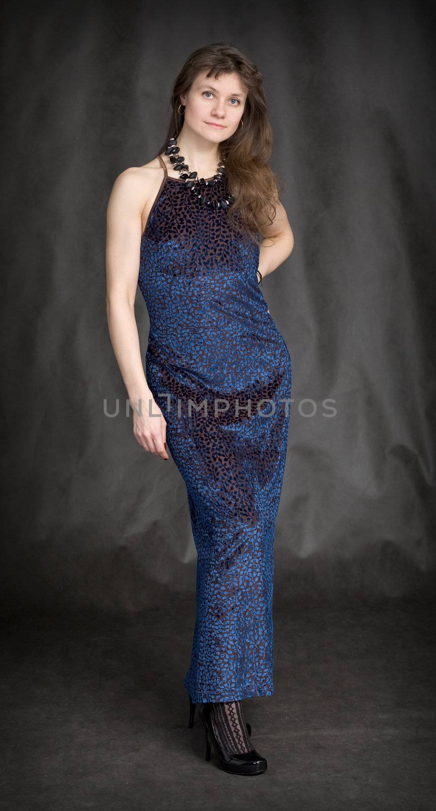The girl in a dark blue evening dress on a black background