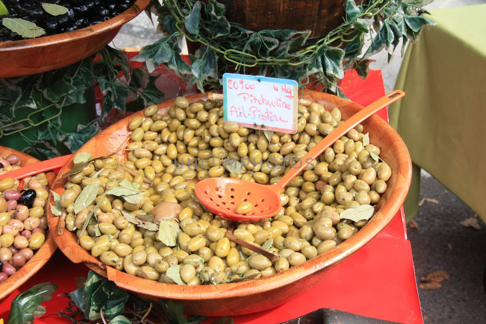 A ceramic bowl, filled with marinated green olives on a french market