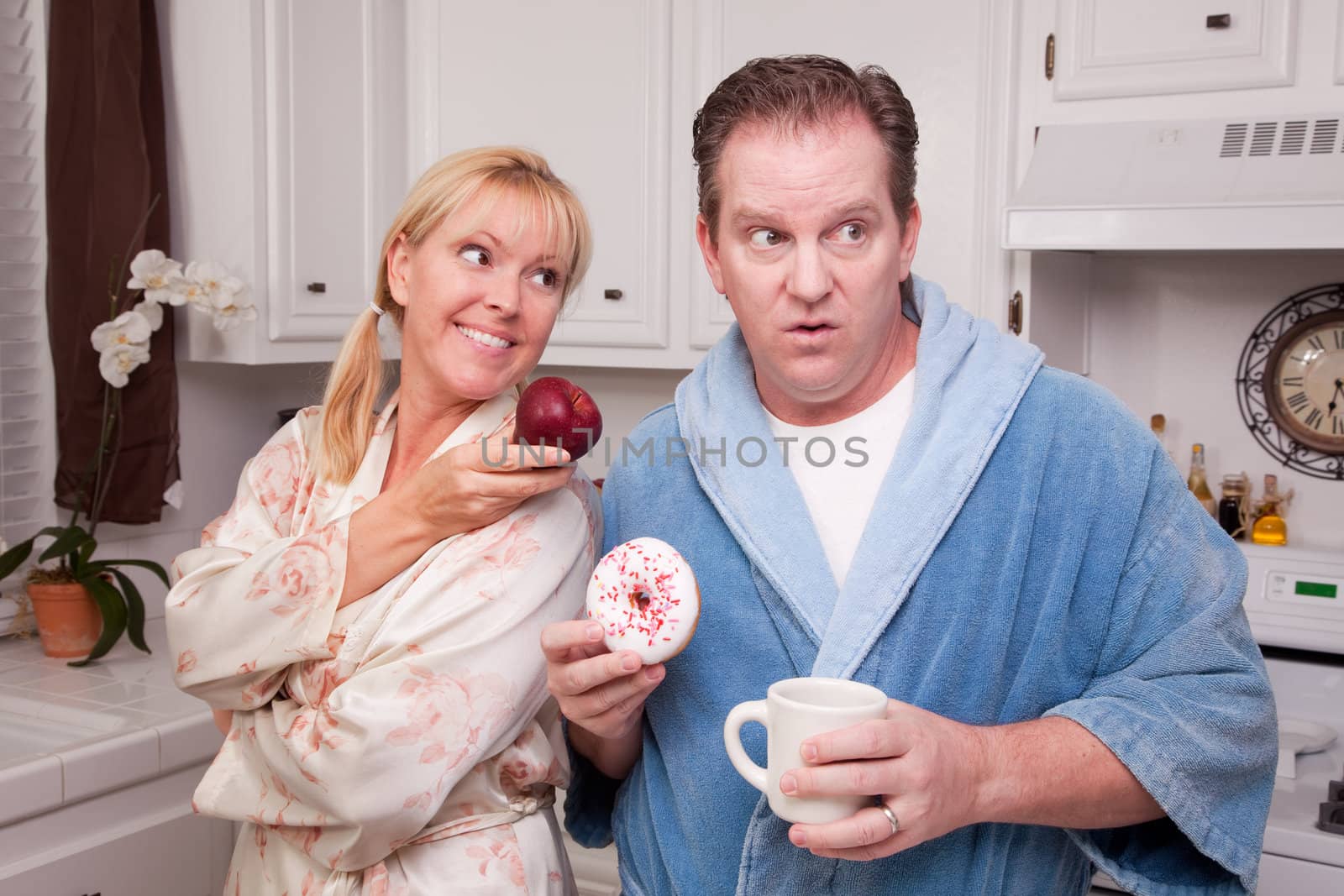 Couple in Kitchen Eating Donut and Coffee or Healthy Fruit.