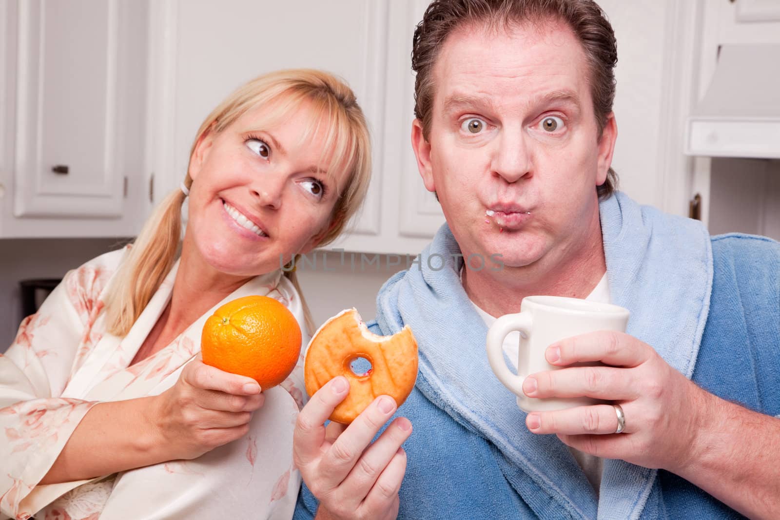 Couple in Kitchen Eating Donut and Coffee or Healthy Fruit.