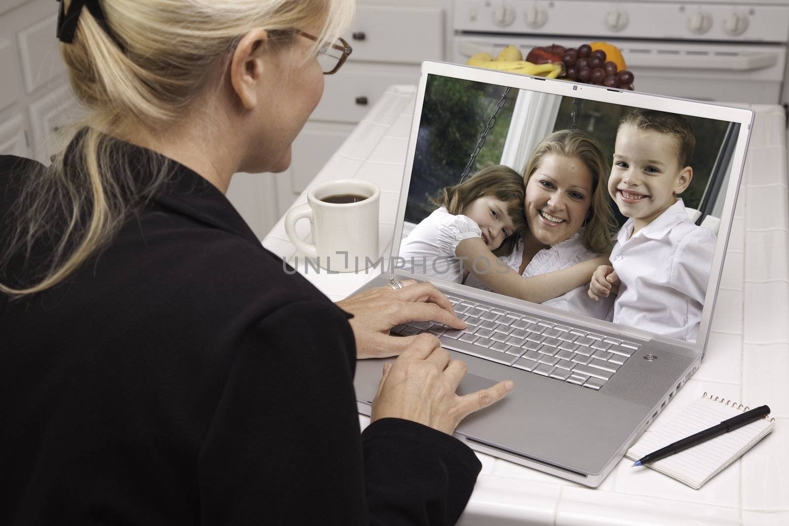 Woman In Kitchen Using Laptop See Friends and Family. Screen can be easily used for your own message or picture. Picture on screen is my copyright as well.
