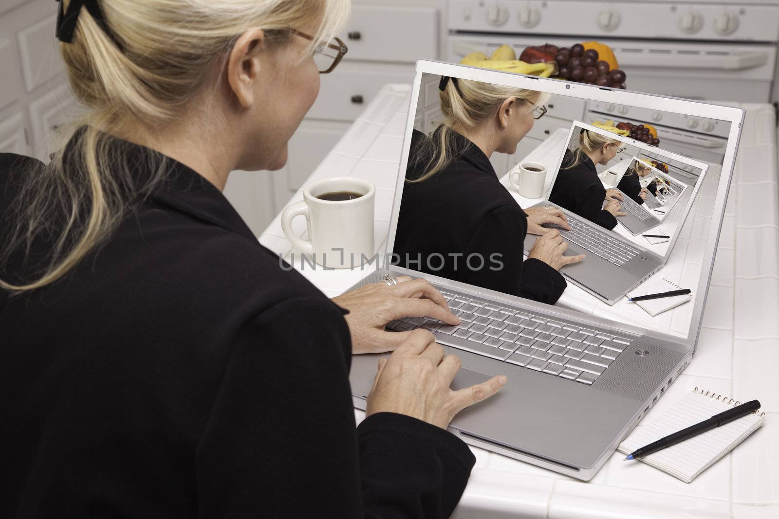 Woman In Kitchen Using Laptop. Screen can be easily used for your own message or picture. Picture on screen is my copyright as well.