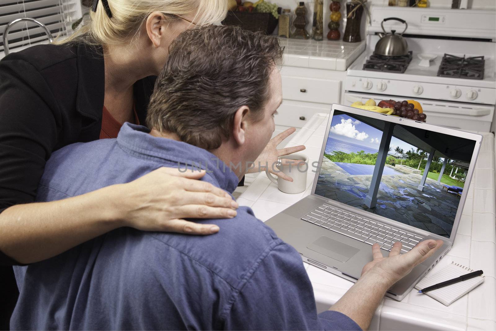 Couple In Kitchen Using Laptop to Research Travel and Vacations. Screen can be easily used for your own message or picture. Picture on screen is my copyright as well.