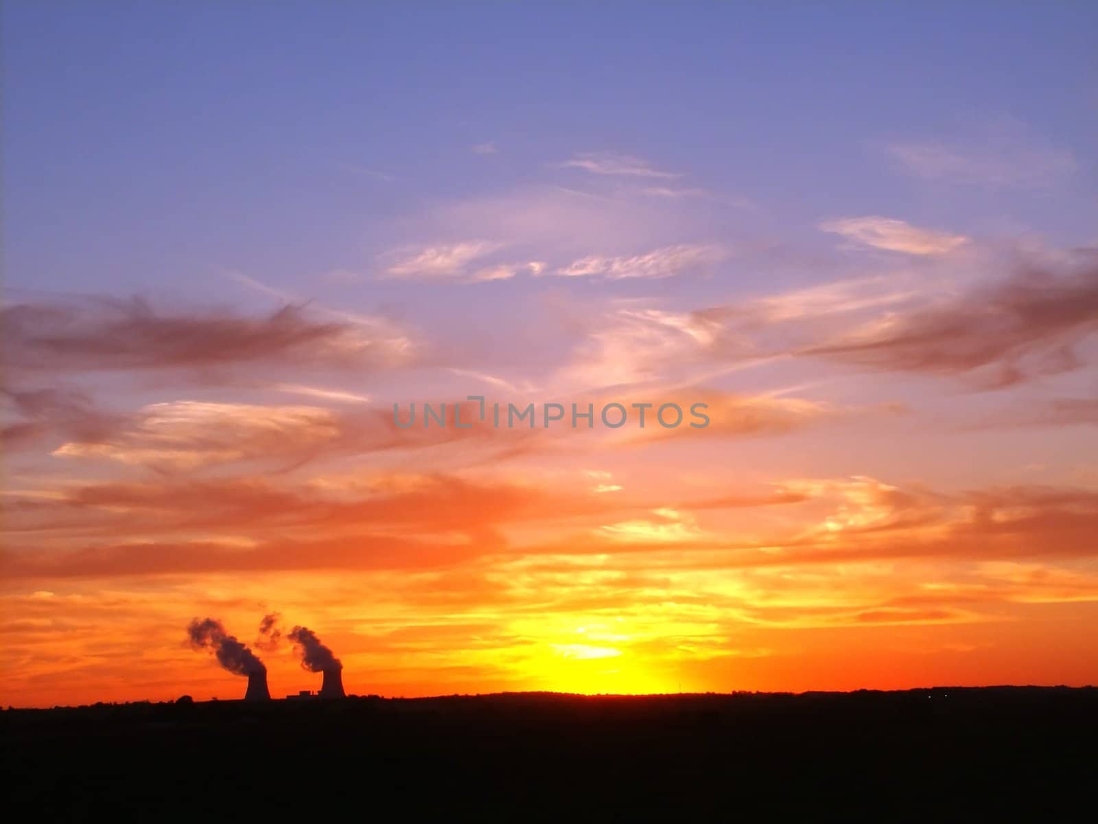 The sun sets over two cooling towers at a nuclear plant.
