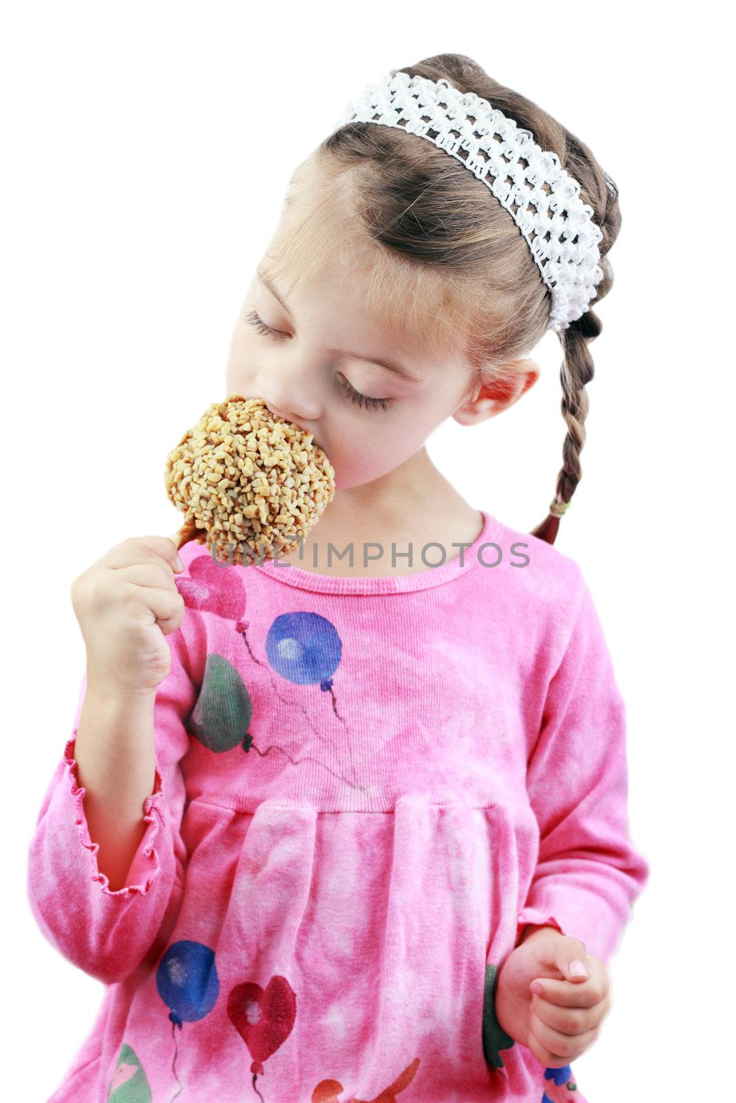 Adorable little girl eats a caramel apple against a white background.