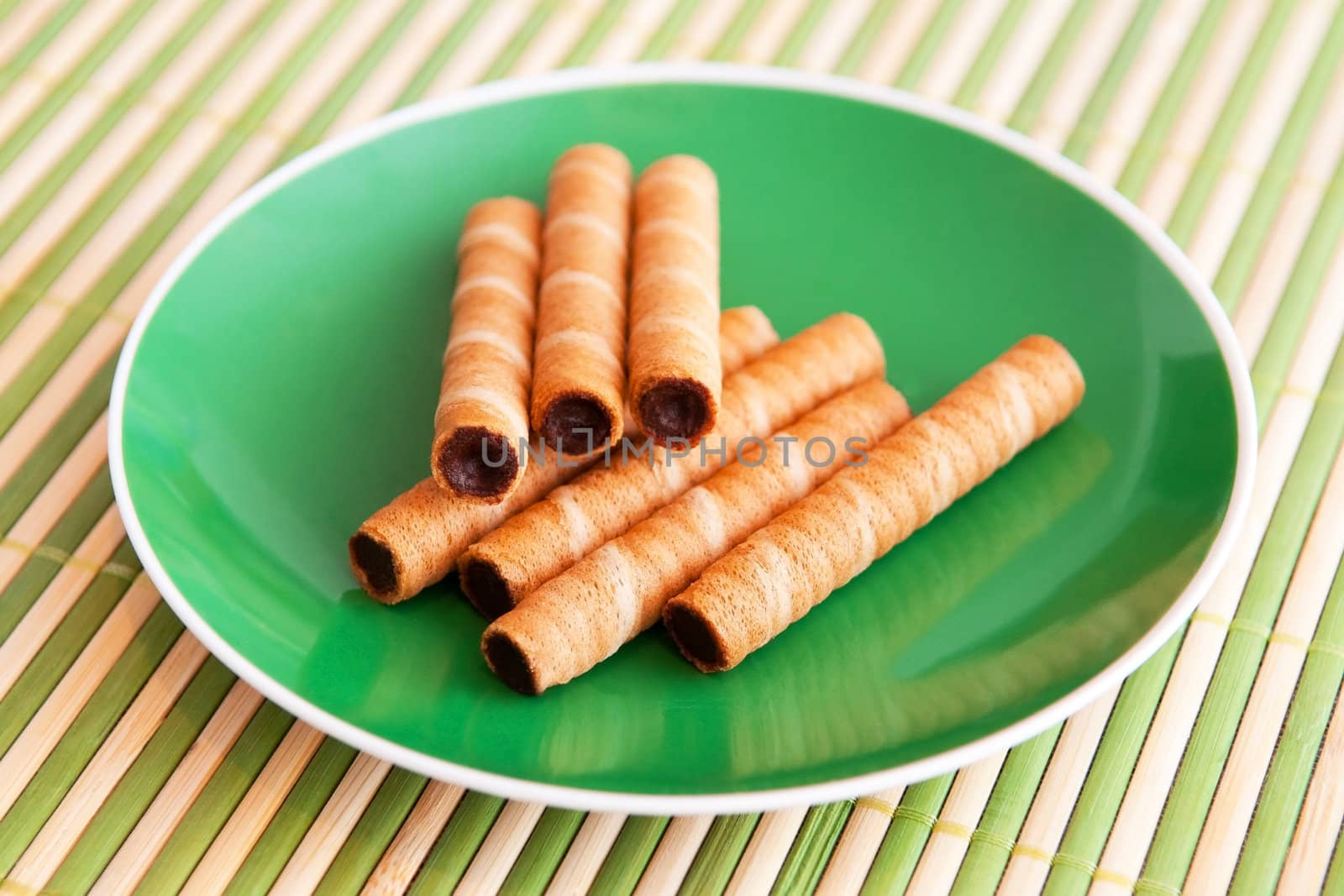 Wafer rolls with chocolate on the green plate