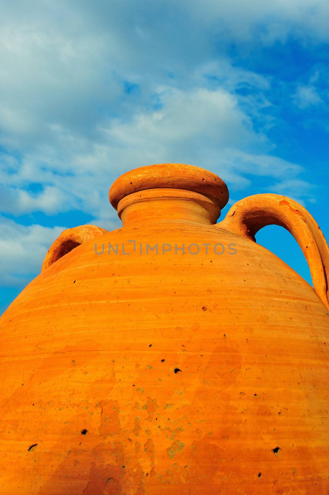 Large ceramic Greek pot against a partially clouded blue Mediterranean sky 