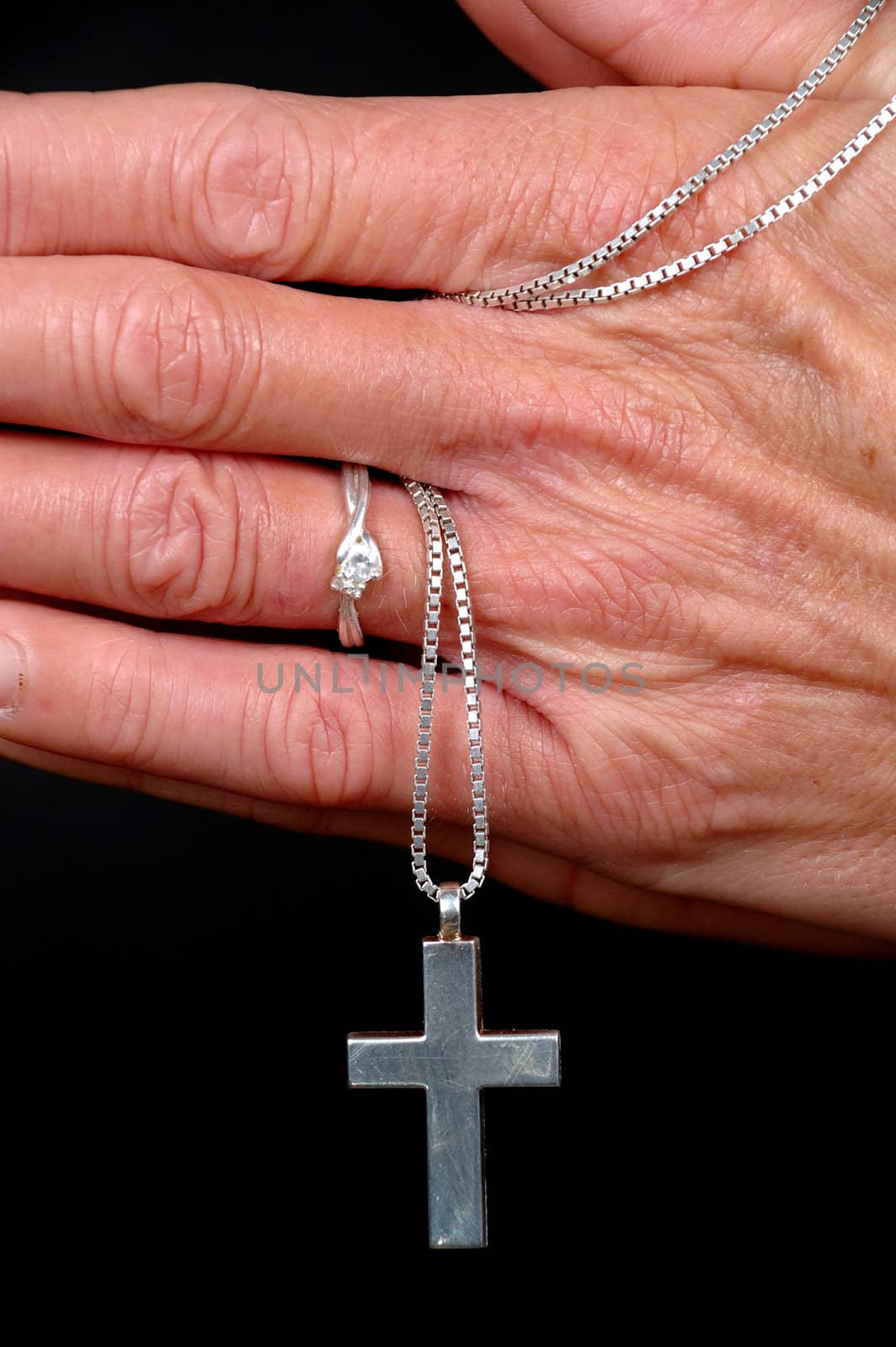 Woman is praying holding her cross. On black clean background.