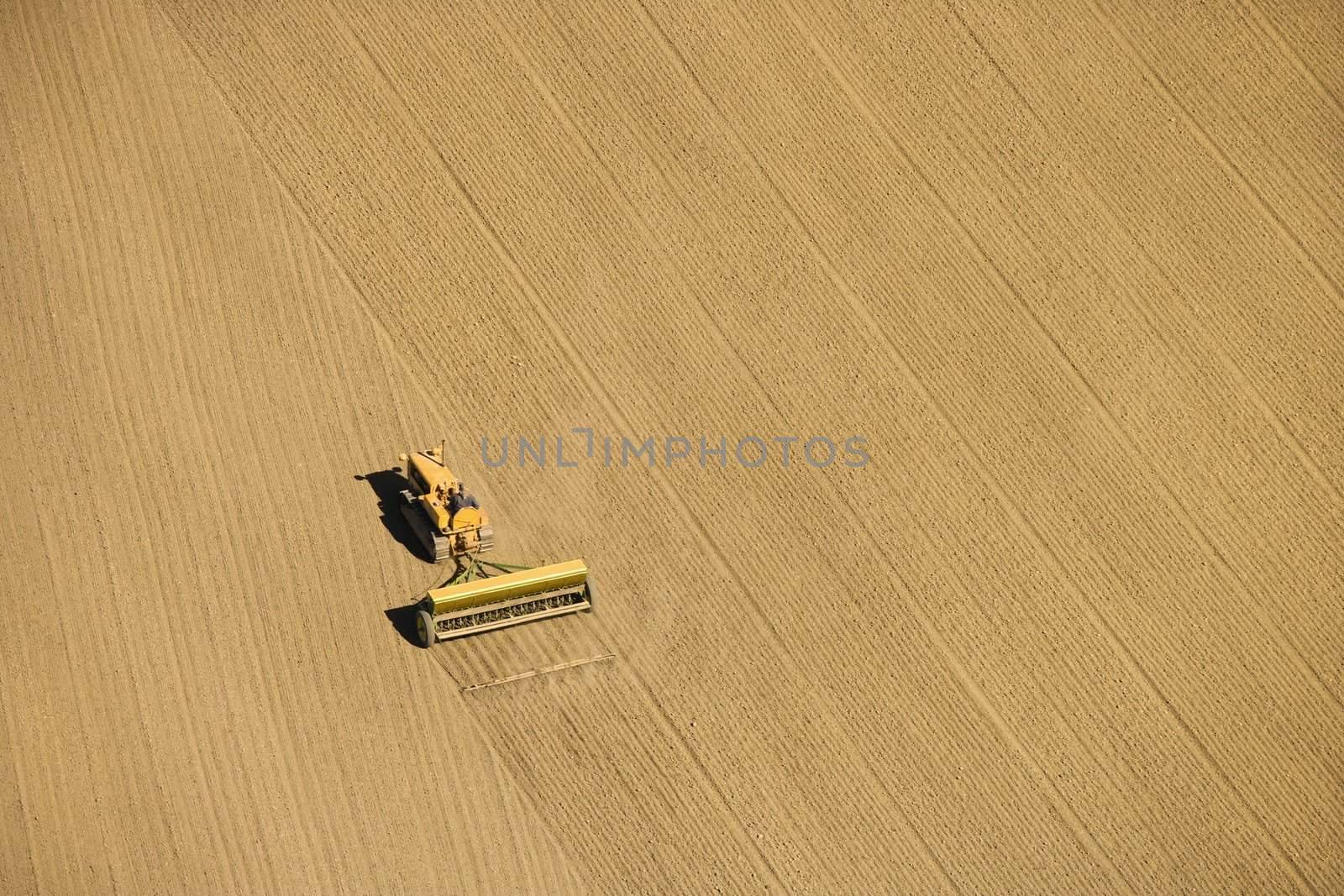 Aerial of farmer tilling crop field in farmland, USA.