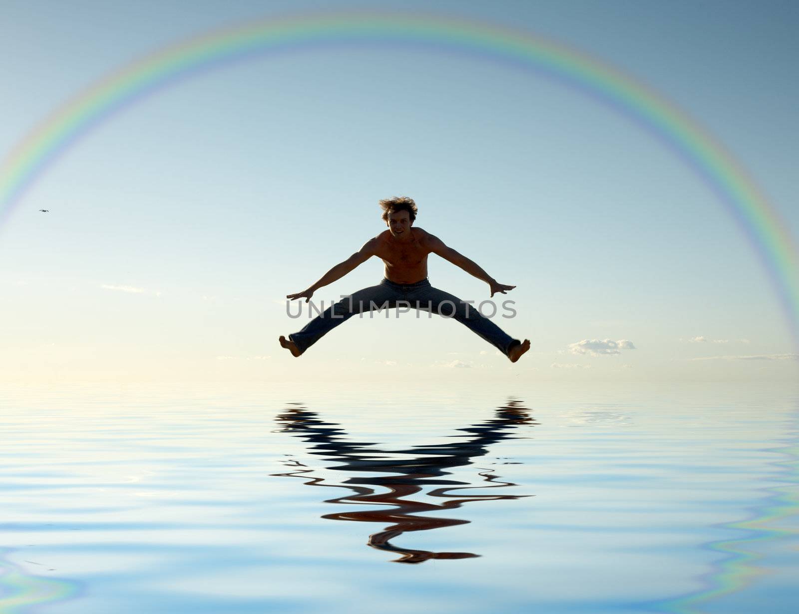 sporty man jumping under big colorful rainbow