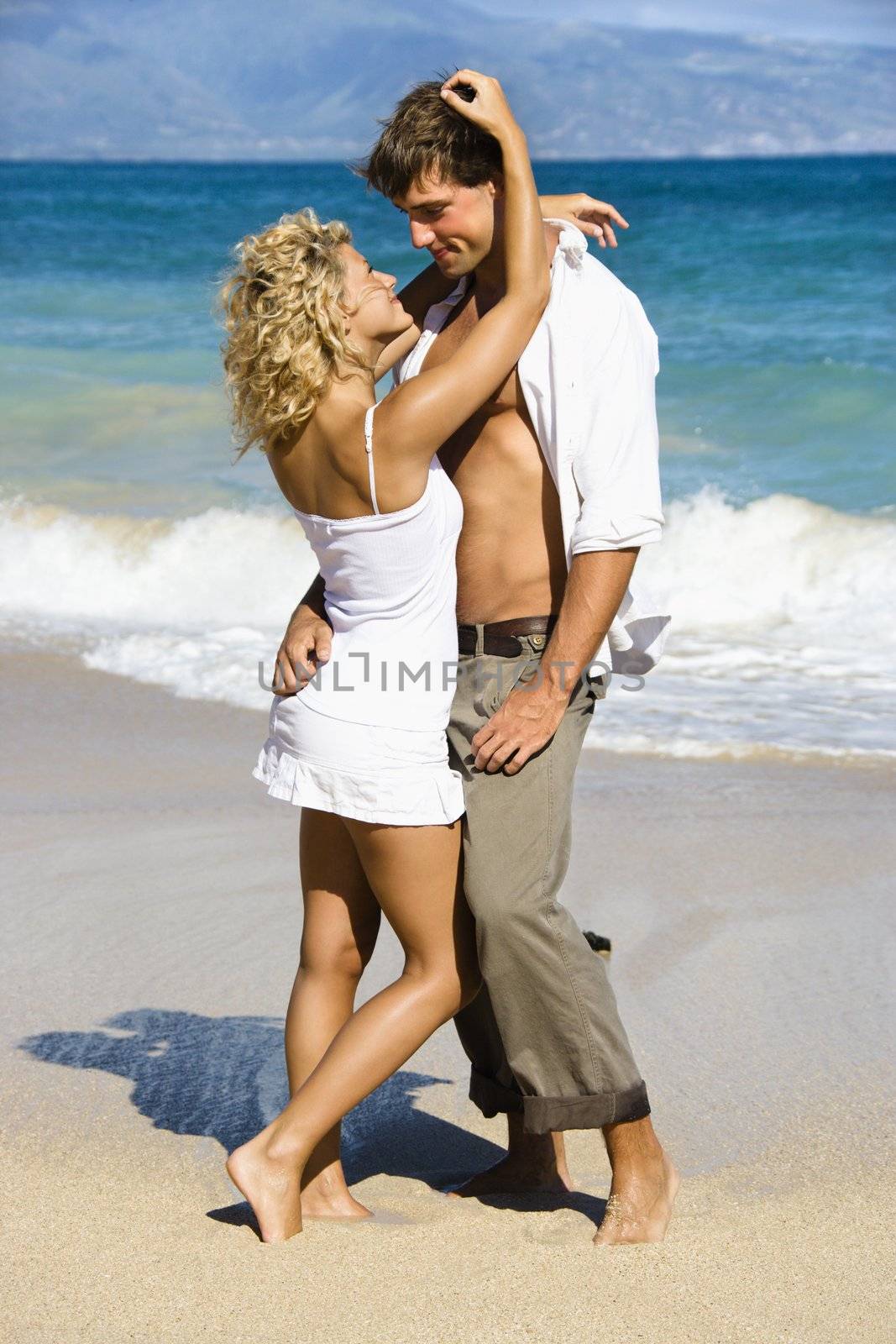 Attractive couple in sensual embrace on Maui, Hawaii beach.