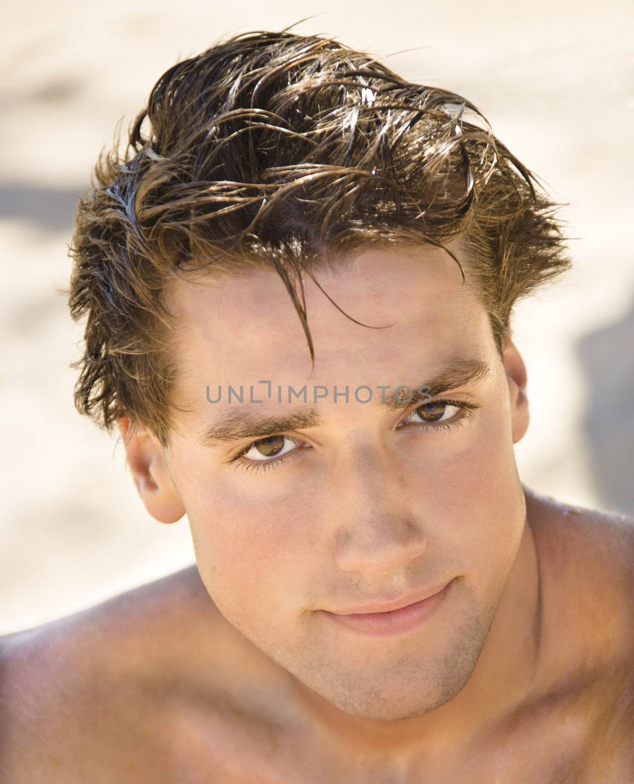 Head and shoulder portrait of handsome man on beach.