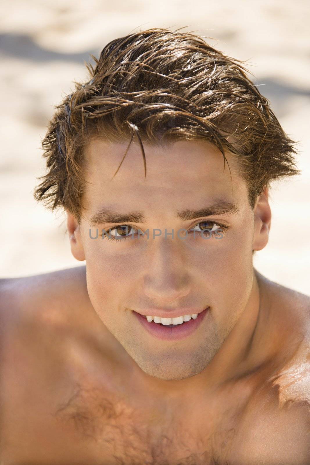 Head and shoulder portrait of handsome man on beach.