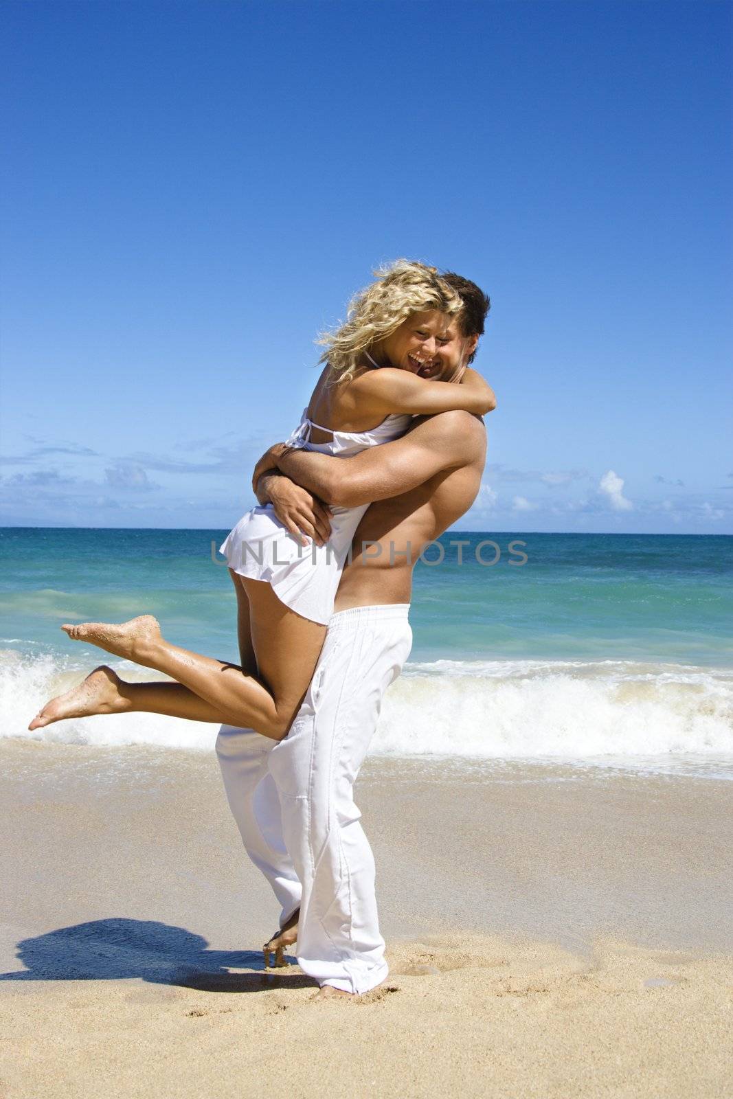 Couple in emotional embrace on Maui, Hawaii beach.