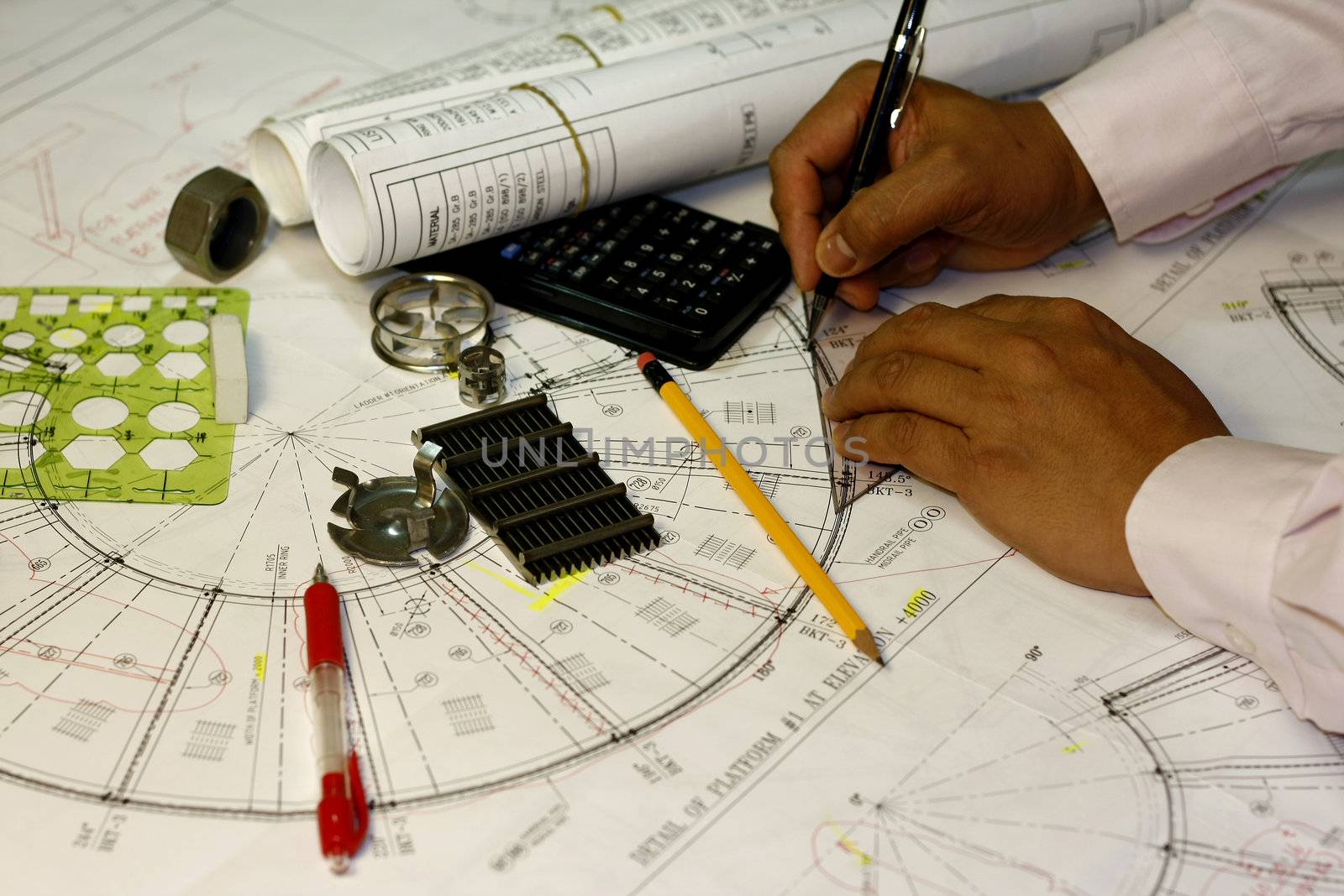 the engineers hand with mechanical pencil and blueprints