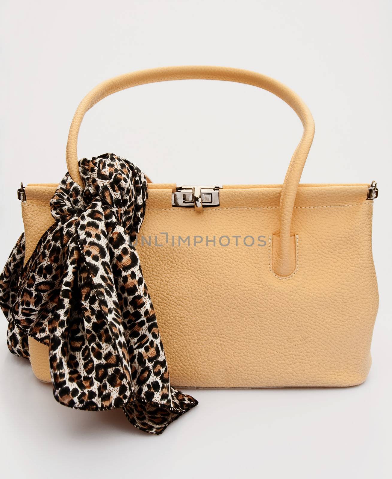 A cream colored female handbag in fifties style with a leopard patterned scarf
