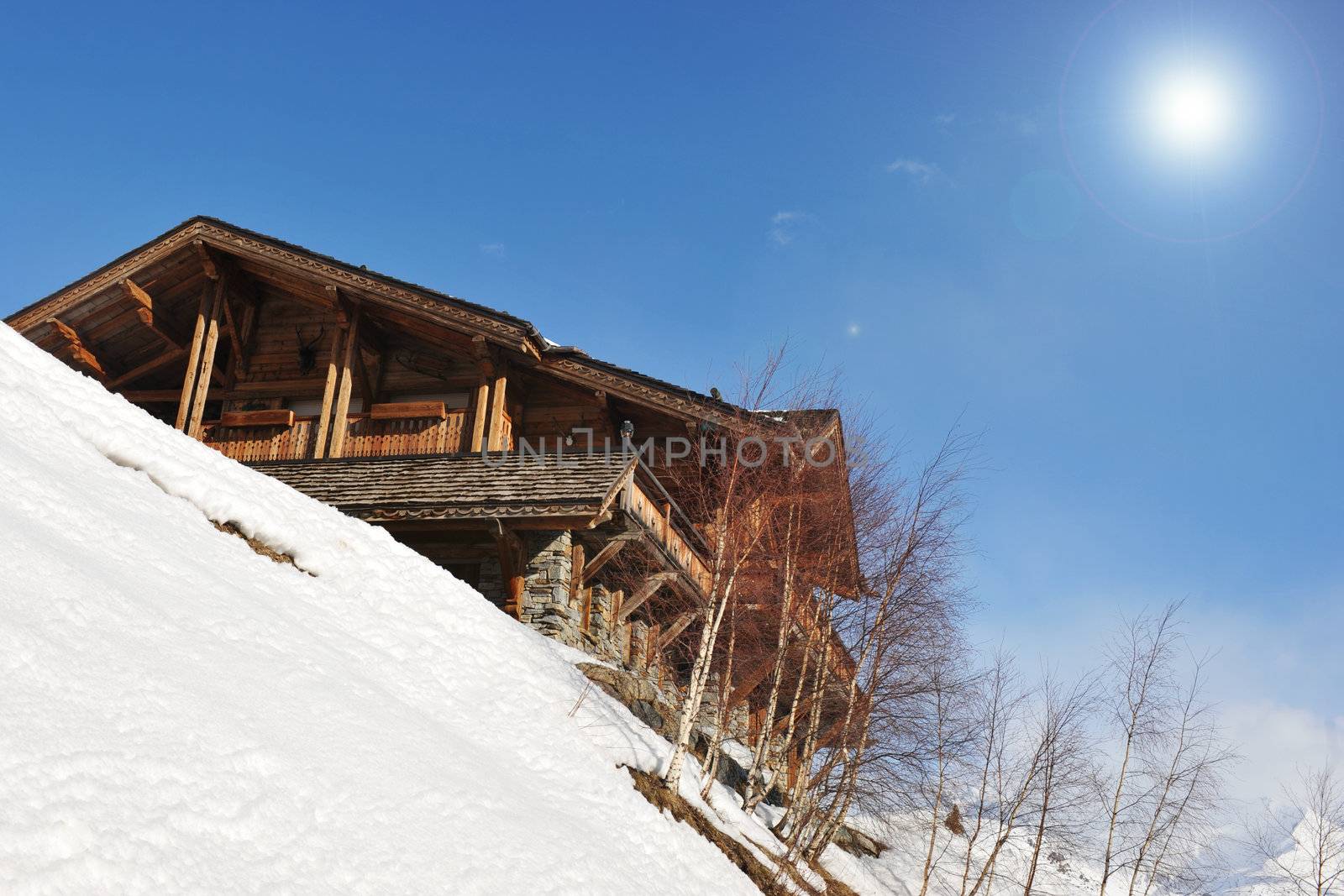 mountain chalet and snow with blue sky and sun