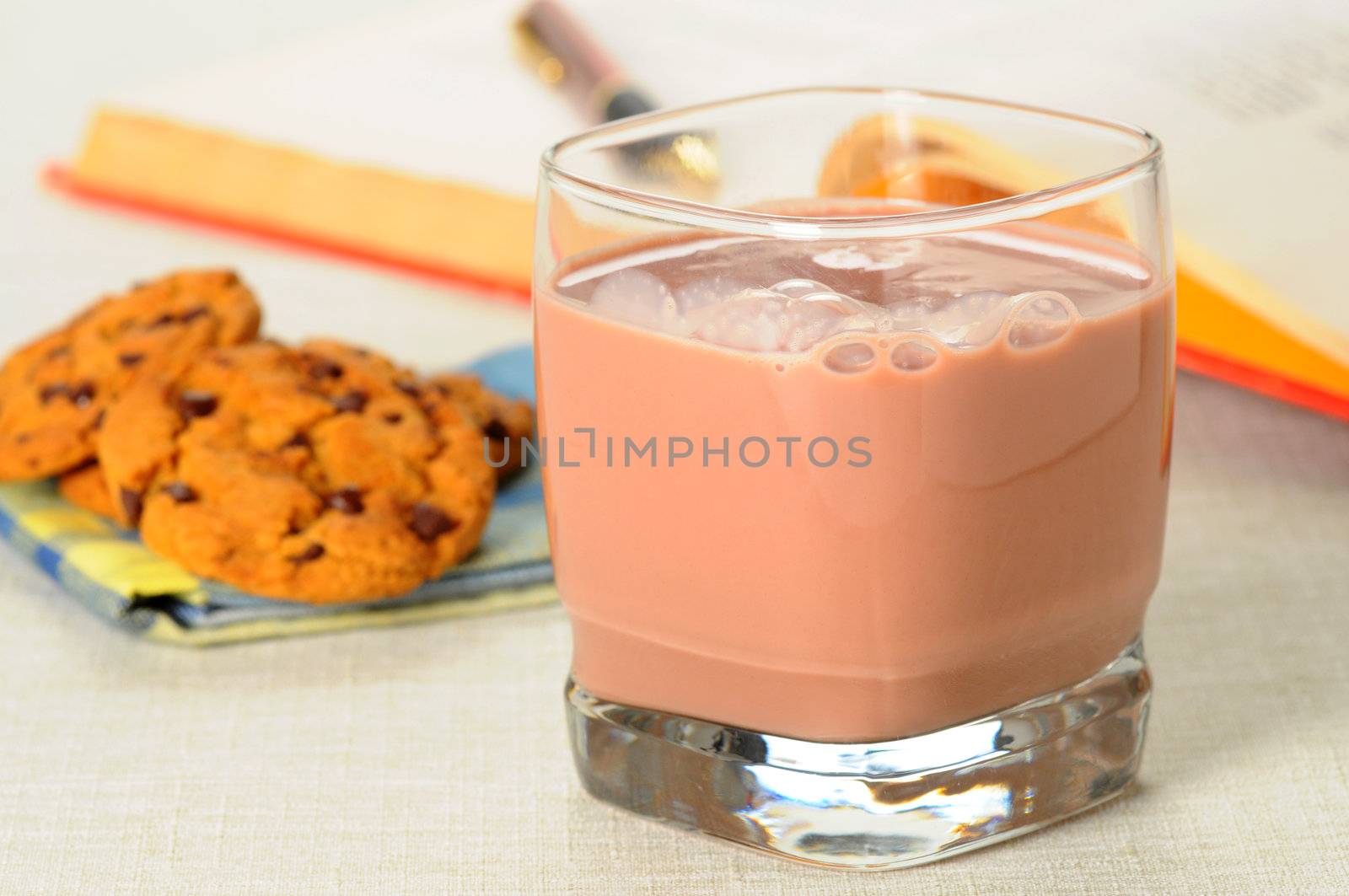 Glass of refreshing chocolate milk with cookies in the background.