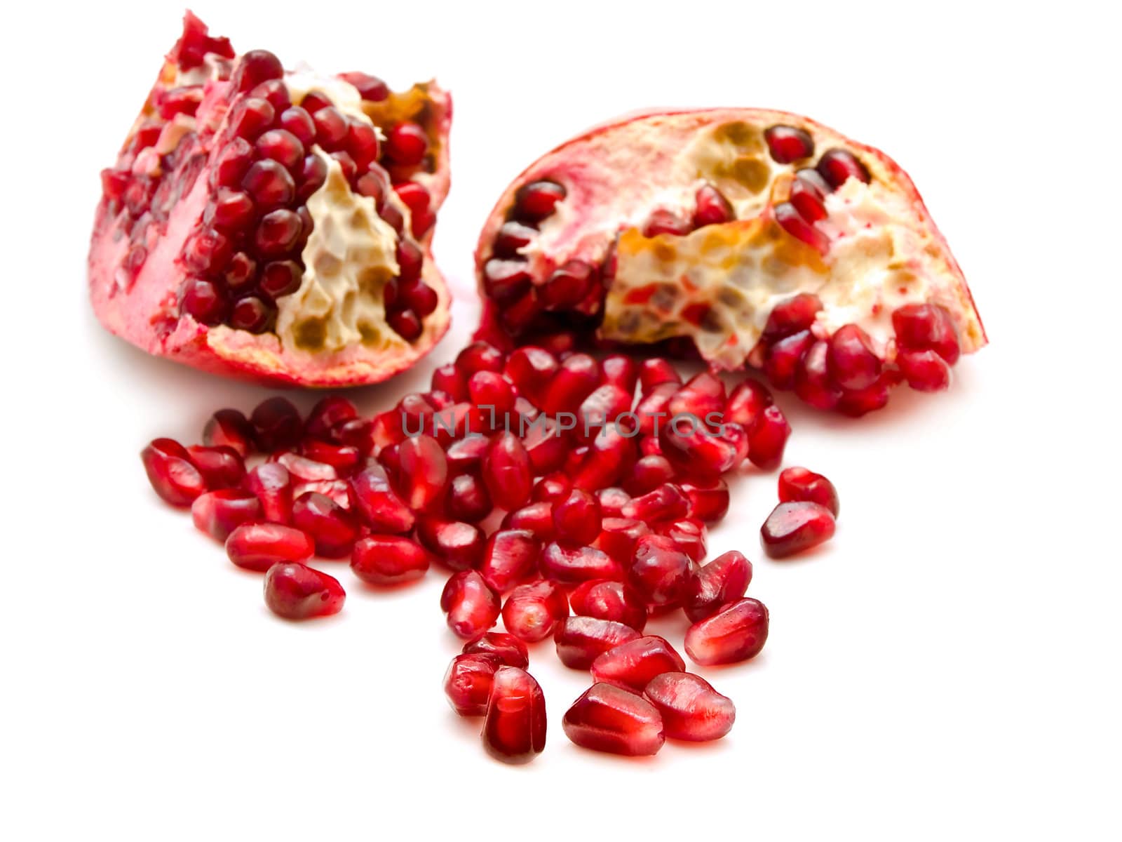 broken red pomegranate and seeds over the white