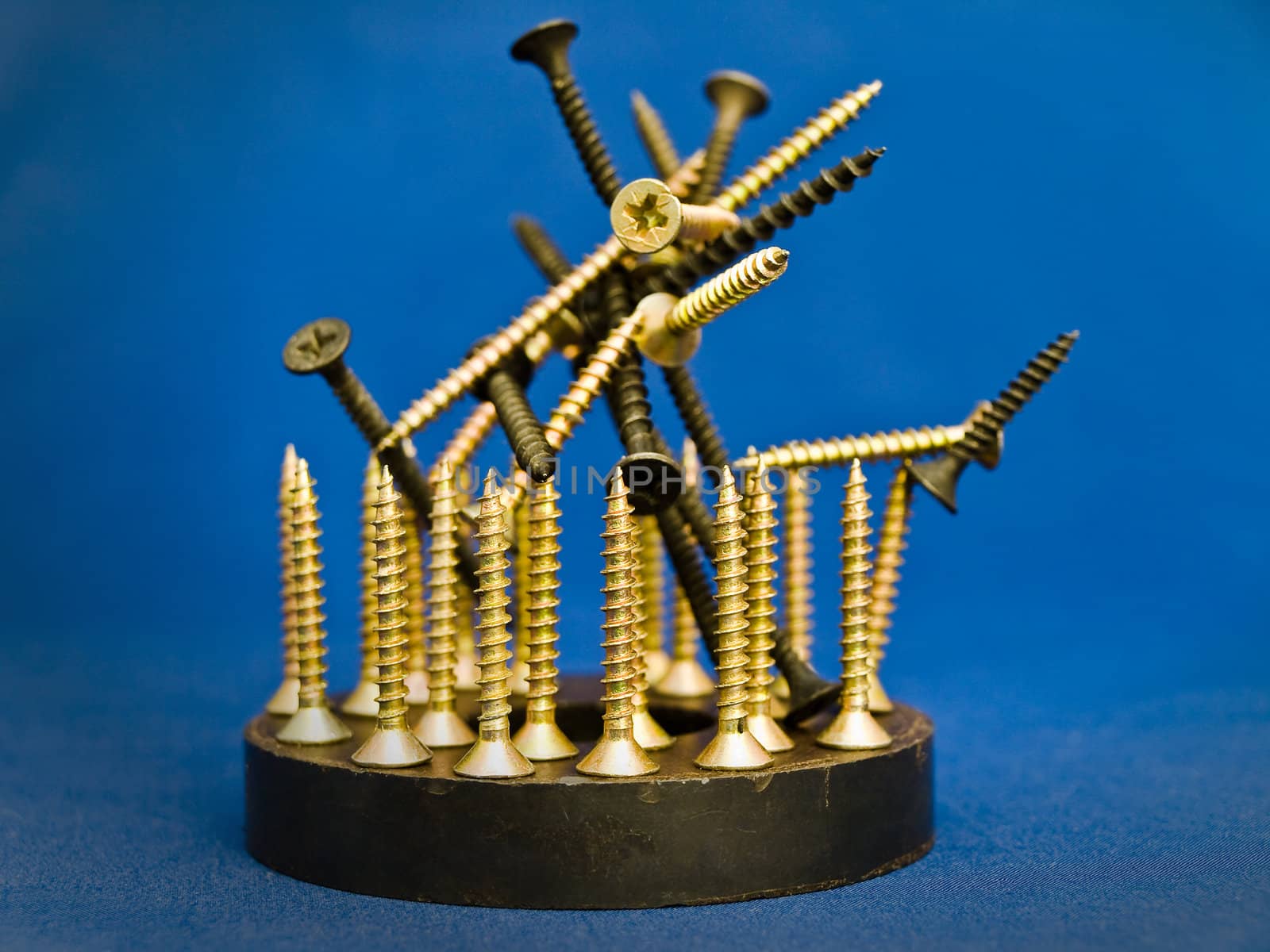industrial sculpture with screws and magnet against the blue background