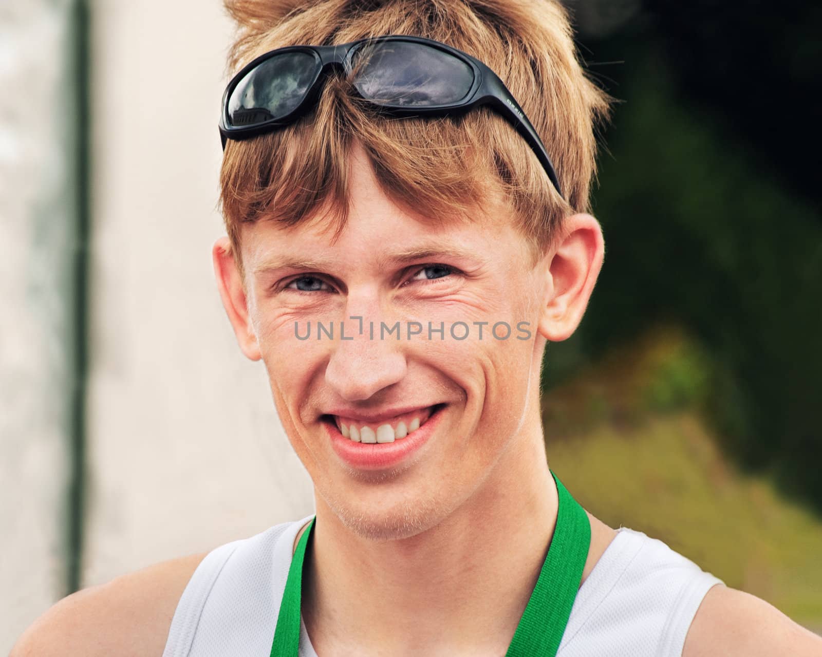 Portrait of the young smiling sportsman in dark glasses