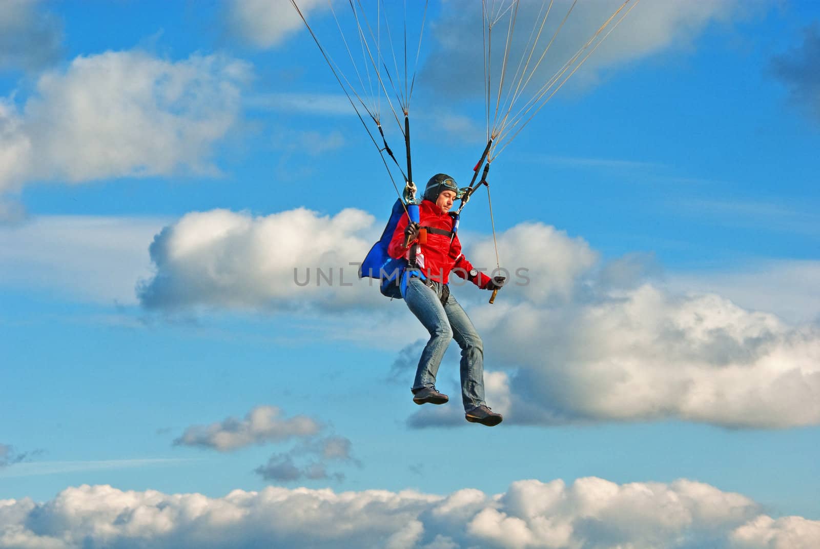 The young girl parachutist in cloudy sky  operates a parachute