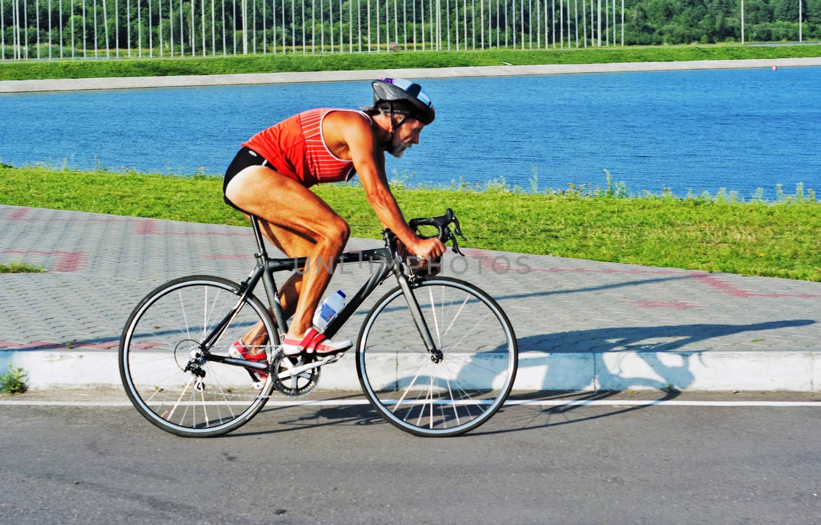 The elderly sportsman goes on a bicycle on a bicycle path